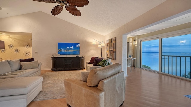 living room featuring ceiling fan, vaulted ceiling, a textured ceiling, and hardwood / wood-style floors