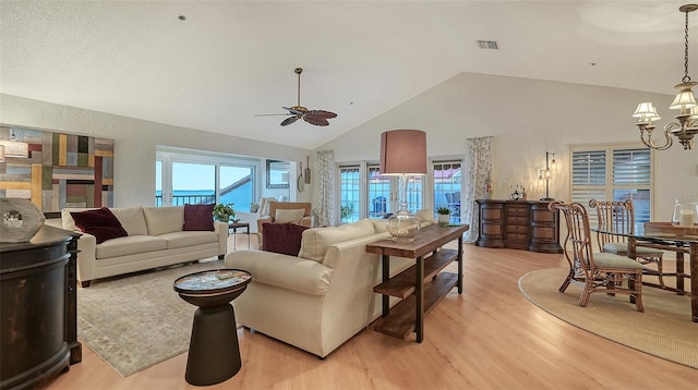 living room with lofted ceiling, light wood-type flooring, and ceiling fan with notable chandelier