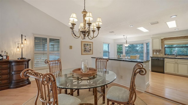 dining room with sink, lofted ceiling, a notable chandelier, and light wood-type flooring