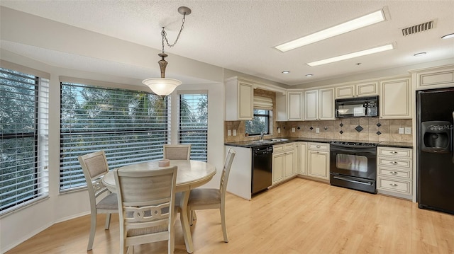 kitchen featuring decorative light fixtures, decorative backsplash, cream cabinets, and black appliances