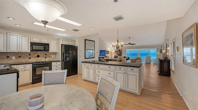 kitchen featuring ceiling fan with notable chandelier, decorative light fixtures, black appliances, and cream cabinetry