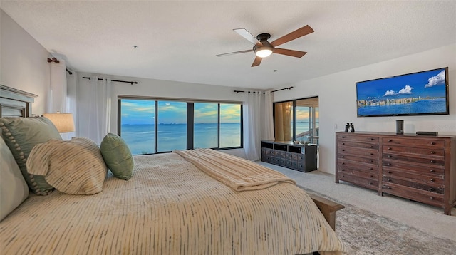 bedroom featuring access to outside, light colored carpet, ceiling fan, and a textured ceiling