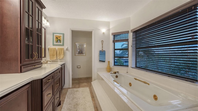 bathroom featuring a relaxing tiled tub, a textured ceiling, vanity, and tile patterned flooring