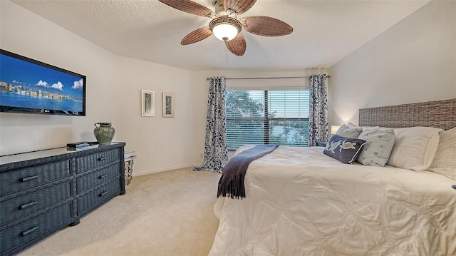 bedroom with ceiling fan, light colored carpet, and a textured ceiling