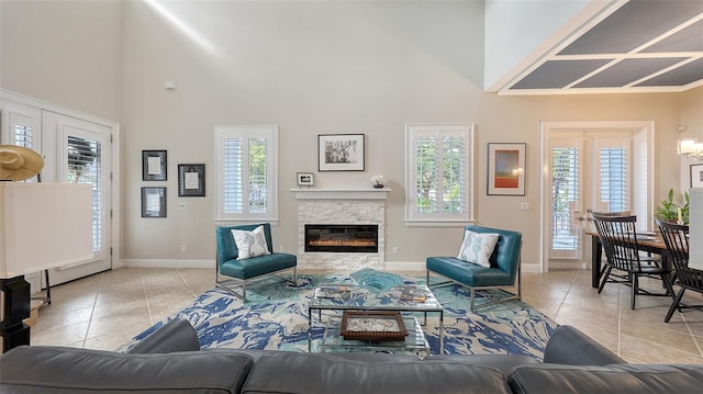 living room featuring light tile patterned flooring, a towering ceiling, and a stone fireplace