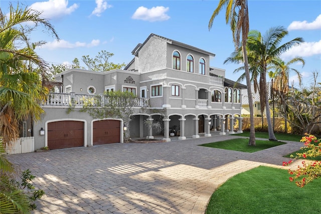 mediterranean / spanish-style home with a garage, a balcony, and a front lawn