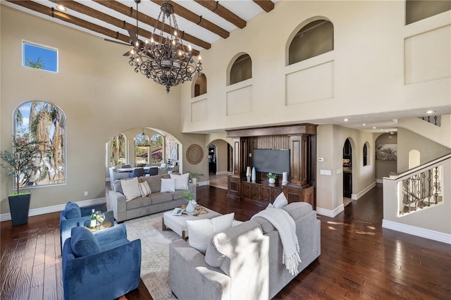 living room with a notable chandelier, dark hardwood / wood-style floors, beam ceiling, and a towering ceiling