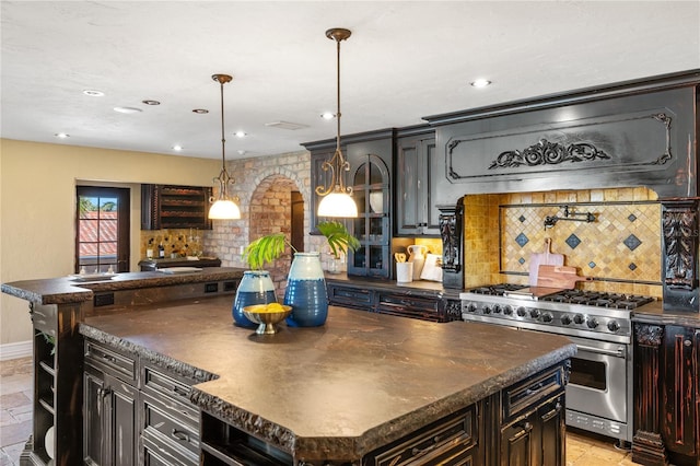 kitchen with decorative backsplash, a center island, luxury stove, and hanging light fixtures