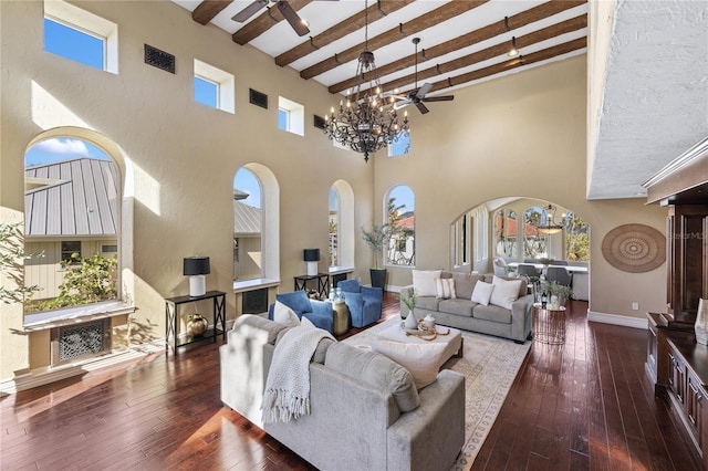 living room with beamed ceiling, a towering ceiling, dark hardwood / wood-style floors, and ceiling fan with notable chandelier