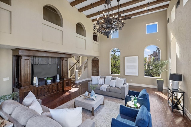 living room featuring beamed ceiling, wood-type flooring, a high ceiling, and an inviting chandelier