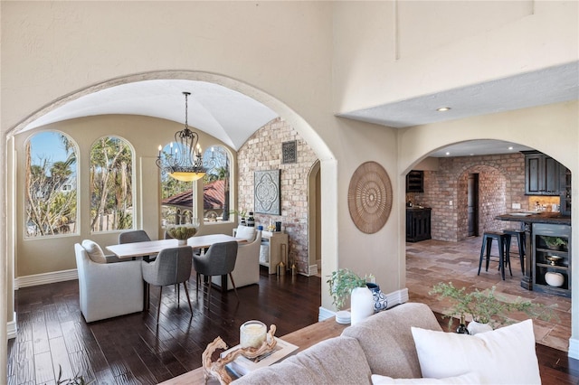 living room with dark hardwood / wood-style flooring, vaulted ceiling, and an inviting chandelier