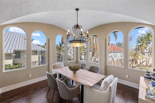 dining room featuring plenty of natural light, vaulted ceiling, dark hardwood / wood-style flooring, and an inviting chandelier