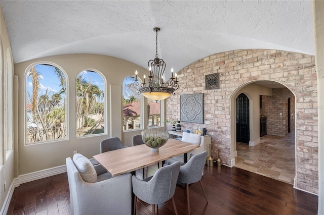 8855 Midnight Pass Rd, Sarasota, FL 34242 - dining room featuring a chandelier, arched walkways, vaulted ceiling, and dark wood-type flooring