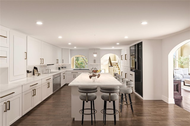 kitchen with backsplash, light stone counters, white cabinetry, dark hardwood / wood-style floors, and a kitchen island