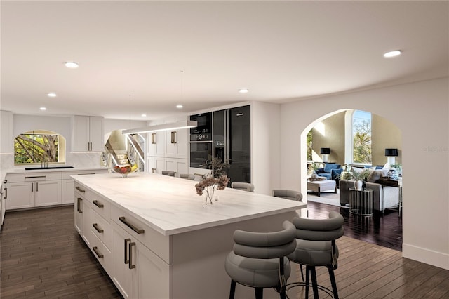 8855 Midnight Pass Rd, Sarasota, FL 34242 - kitchen featuring recessed lighting, arched walkways, a kitchen island, dark wood-style flooring, and backsplash