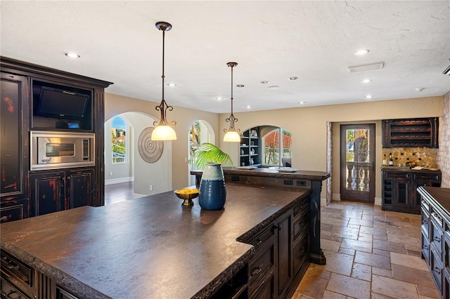 8855 Midnight Pass Rd, Sarasota, FL 34242 - kitchen featuring arched walkways, stainless steel microwave, dark countertops, healthy amount of natural light, and recessed lighting