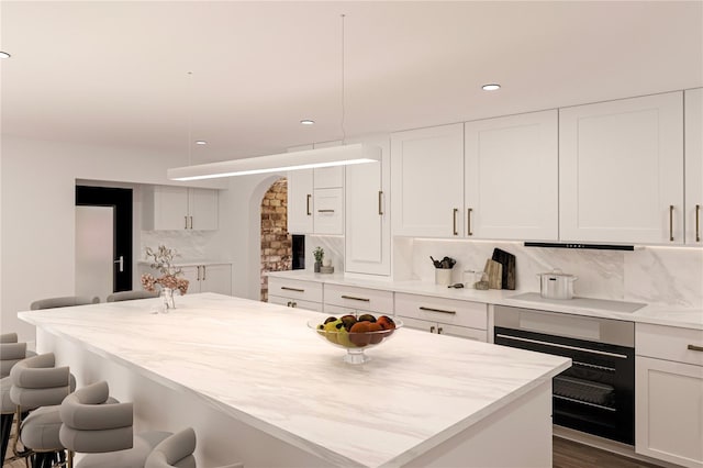 8855 Midnight Pass Rd, Sarasota, FL 34242 - kitchen featuring oven, a breakfast bar, backsplash, white cabinets, and recessed lighting
