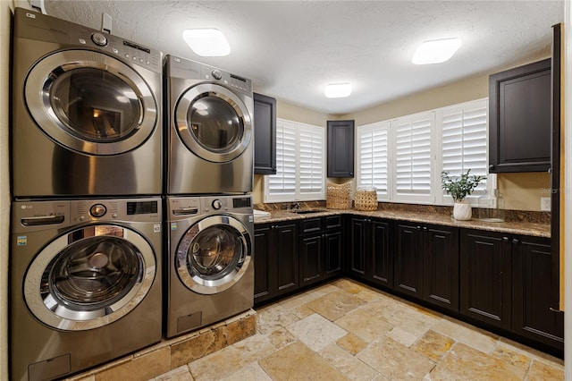 8855 Midnight Pass Rd, Sarasota, FL 34242 - laundry area featuring washing machine and clothes dryer, cabinet space, stone tile floors, stacked washing machine and dryer, and a textured ceiling