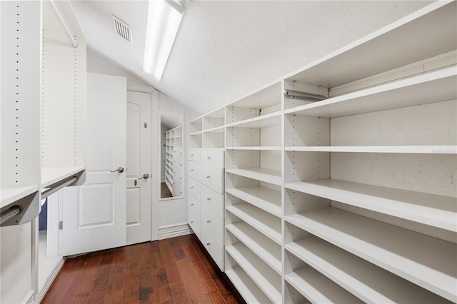 spacious closet with dark hardwood / wood-style floors and lofted ceiling