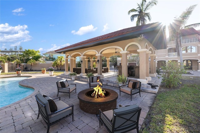 view of patio / terrace featuring an outbuilding, an outdoor kitchen, a fenced in pool, and a fire pit