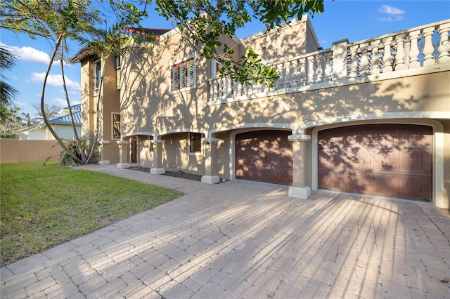 view of front of property featuring a balcony, a front yard, and a garage