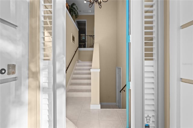 stairway with an inviting chandelier and tile patterned flooring