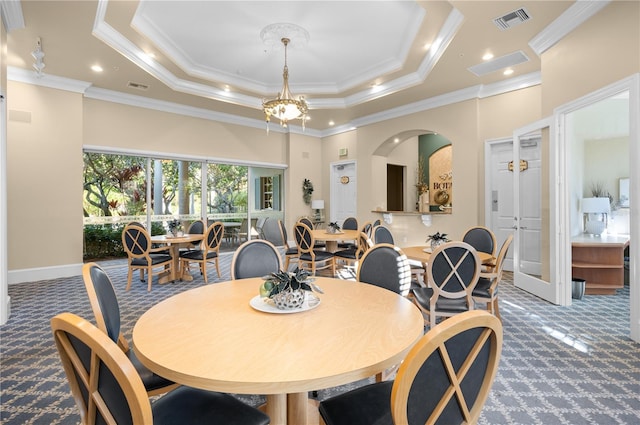 dining area with an inviting chandelier, ornamental molding, a raised ceiling, and carpet flooring