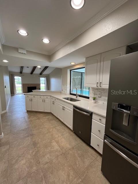 kitchen featuring sink, white cabinetry, stainless steel fridge, dishwasher, and kitchen peninsula