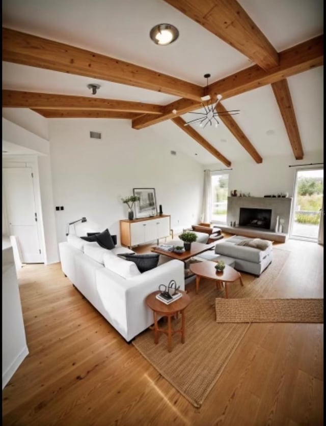 living room with ceiling fan, lofted ceiling with beams, and light wood-type flooring