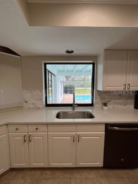 kitchen featuring dishwasher, sink, white cabinets, and decorative backsplash