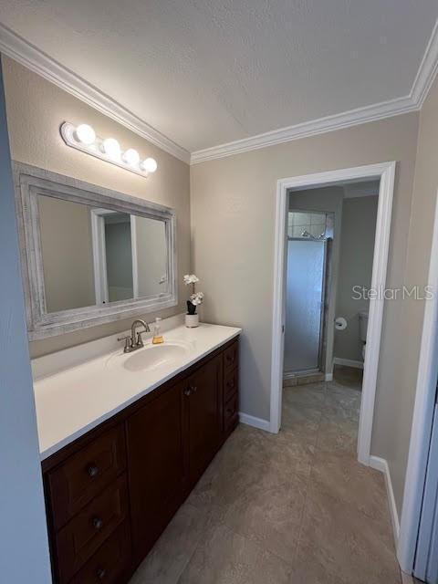 bathroom featuring crown molding, vanity, toilet, and walk in shower