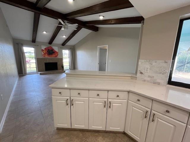 kitchen with vaulted ceiling with beams, white cabinetry, kitchen peninsula, ceiling fan, and backsplash