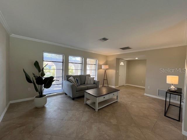 living room featuring baseboards, visible vents, and ornamental molding