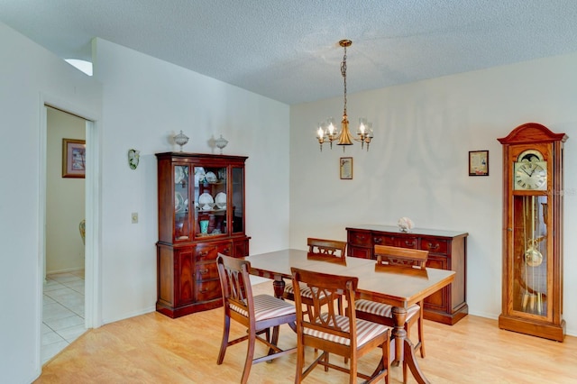 dining room with light hardwood / wood-style floors, a textured ceiling, and a chandelier