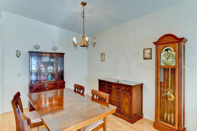 dining space with a chandelier, a textured ceiling, and light hardwood / wood-style floors