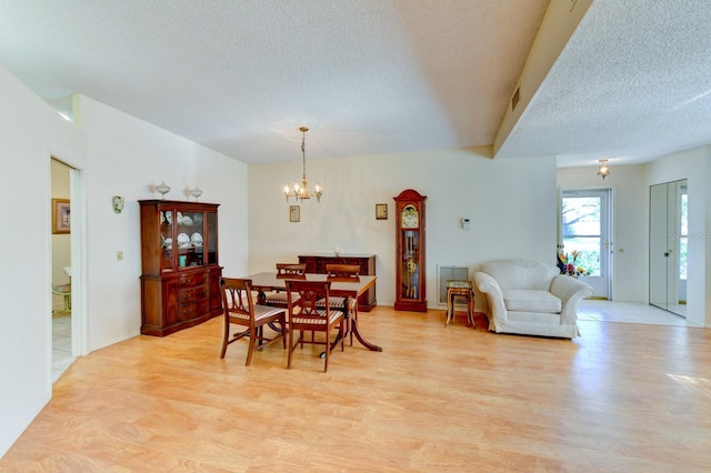 dining area with a notable chandelier, a textured ceiling, and light hardwood / wood-style flooring