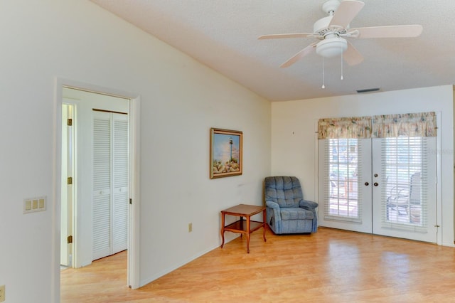 sitting room featuring ceiling fan, french doors, a textured ceiling, and light wood-type flooring