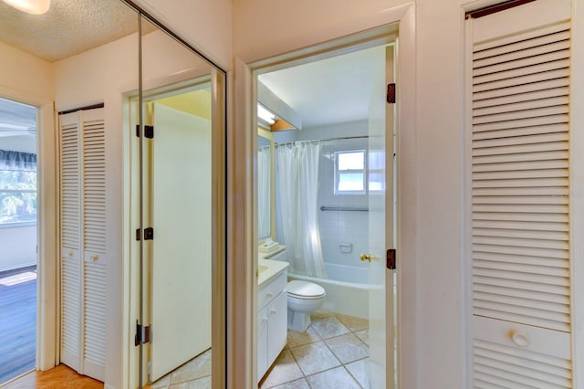 full bathroom with vanity, tile patterned floors, toilet, shower / bathtub combination with curtain, and a textured ceiling