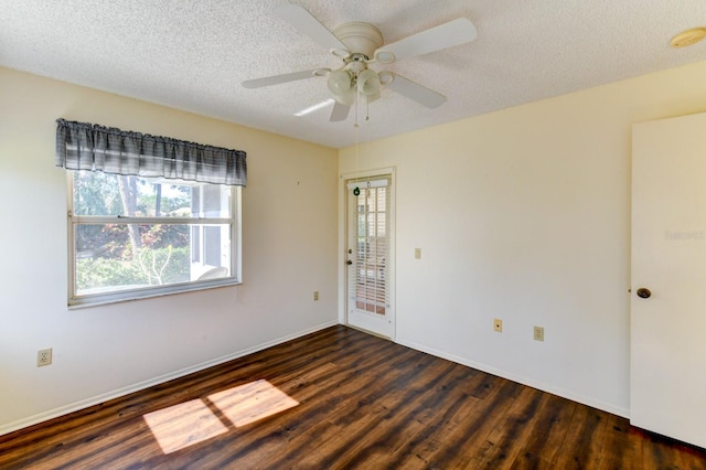 empty room with ceiling fan, a healthy amount of sunlight, dark hardwood / wood-style flooring, and a textured ceiling