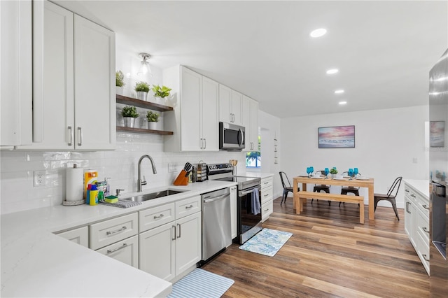 kitchen featuring sink, light hardwood / wood-style flooring, stainless steel appliances, white cabinets, and decorative backsplash