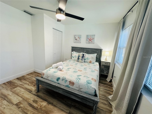 bedroom with multiple windows, hardwood / wood-style flooring, a closet, and ceiling fan