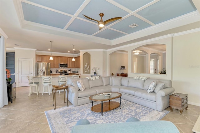 living room with crown molding, ceiling fan, coffered ceiling, and light tile patterned flooring