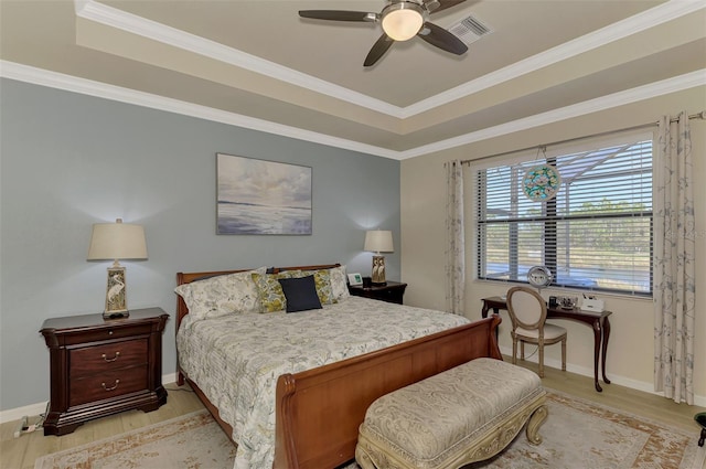 bedroom with light hardwood / wood-style floors, a raised ceiling, ceiling fan, and crown molding