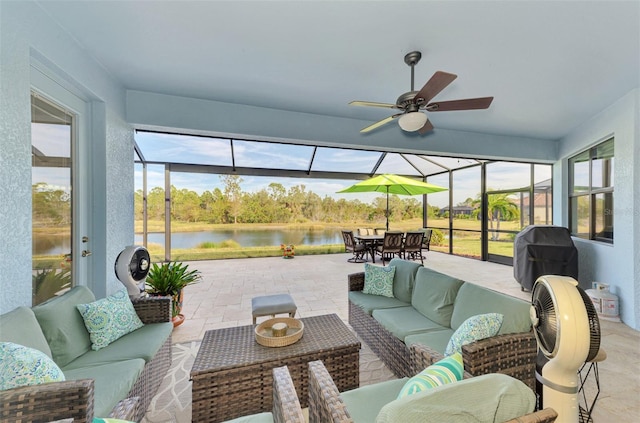 sunroom with ceiling fan, a water view, and a healthy amount of sunlight