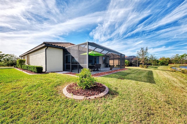 back of house featuring glass enclosure, a patio area, and a yard