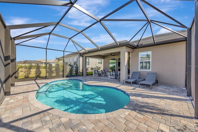 view of pool featuring a patio, glass enclosure, and ceiling fan