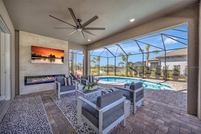 view of patio / terrace with an outdoor living space, glass enclosure, and ceiling fan