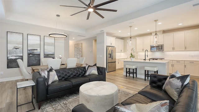 17744 Savory Mist Cir, Bradenton, FL 34211 - living room featuring a tray ceiling, light wood-type flooring, a ceiling fan, and visible vents