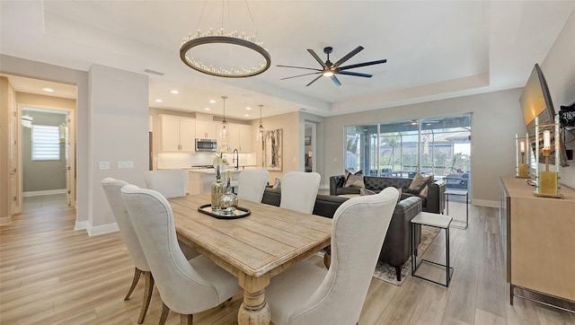 17744 Savory Mist Cir, Bradenton, FL 34211 - dining area with light wood-style floors, a tray ceiling, and baseboards