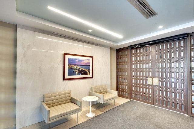 sitting room with a tray ceiling and tile patterned floors